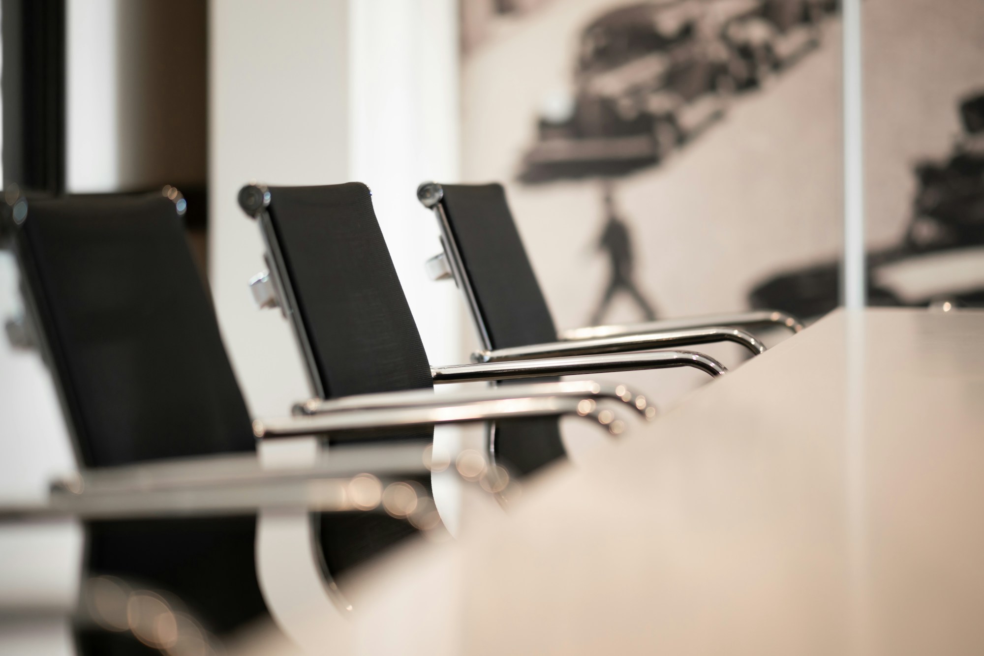 Three chairs spaced around a minimalist meeting table, seen from above